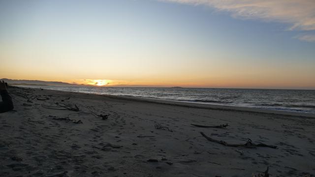 Image shows the sun setting over the Tasman Sea as seen from Haast Beach
