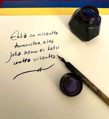 Mustepullo, mustekynä ja käsin kirjoitettu teksti ”Ehkä on viisautta tunnustaa, että joka aamu ei keksi uutta viisautta.”