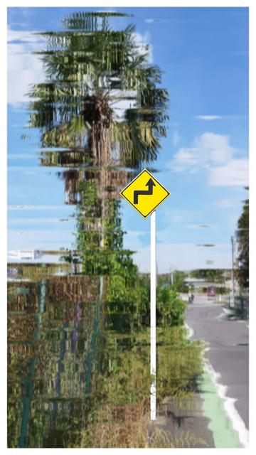 A picture taken on the side of the road. Half of it is in the shot, the other half is the dirt besides it. There is some vegetation on the dirt side and a big palm tree (or something of that kind, I'm not good in biology). In the center of the shot is a yellow diamond shaped warning traffic sign on a metal pole. The warning is about sharp turns ahead. Everything in the picture except for the sign and its pole have been given an effect that warped all objects in a random wave pattern. It looks weird but it's not distorted enough to make it unrecognizable.