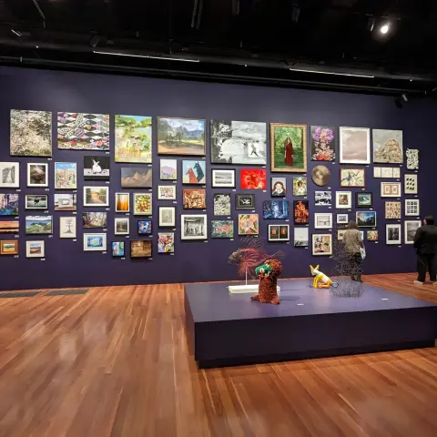 Purple gallery wall and pedestal featuring floor-to-ceiling art and sculptures at the de Young Open 2023.
