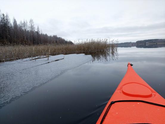 Jäätä ruovikossa. Muutama lumihiutale kajakin kannella.