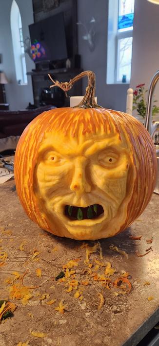 Carved Halloween face in a pumpkin.  Resembles an angry old woman/Witch with straggly hair.