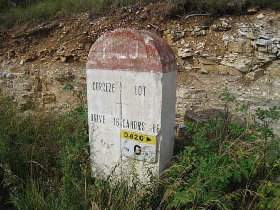 Borne routière de limite de Département en pierre calcaire, sur fond de d'un sol découpé, également en pierre calcaire