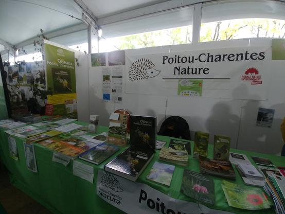 Stand de l'association Poitou-Charentes Nature avec des affiches en fond et des tables avec des brochures et des livres.