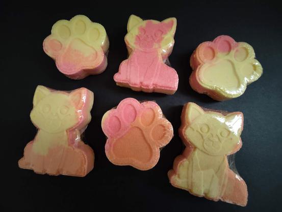 Red, yellow and orange colored bath bombs that are in the shape of paw prints and foxes