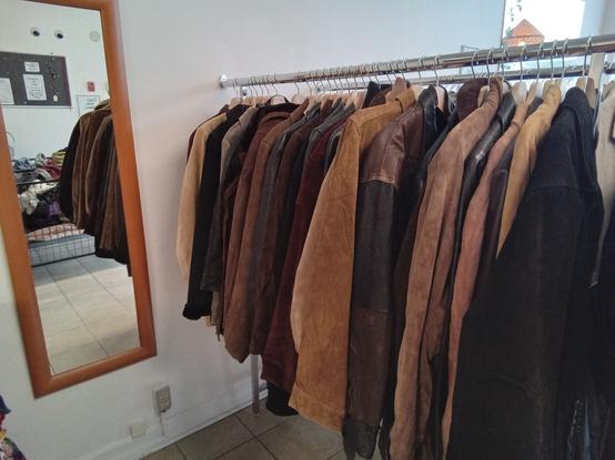 a clothing rack full of suede and leather jackets