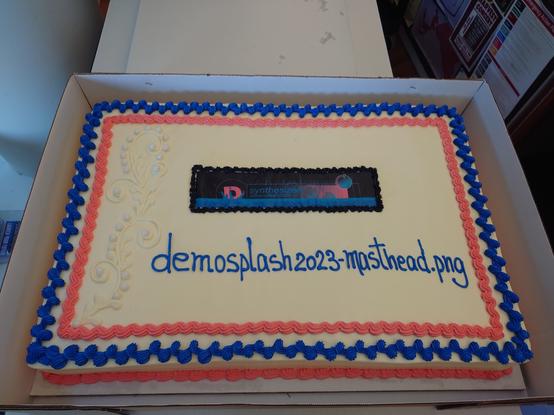A sheet cake with the Demosplash 2023 masthead and "demosplash2023-masthead.png" written in frosting.