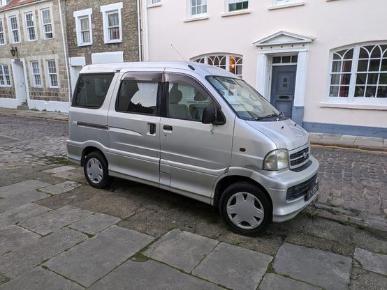 A silver window-van by Daihatsu, parked in the High Street on the lovely island of Alderney. Although it has a dent or two and the odd rust spot, it's still capable of making the arduous drive to the other end of the island, about three miles away.