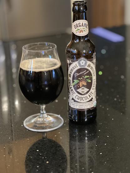 A tulip glass full of dark beer on the left, the source bottle from Samuel Smith to the right. A chocolate stout, the color scheme is predictably brown, tan, and green (leaves)