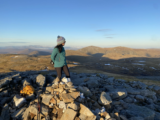 Girl on summit looking away from camera mountains in background