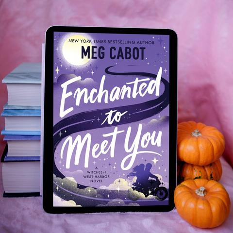 Cover of Enchanted to Meet You on an iPad, next to orange mini pumpkins. There is a pink background, and a stack of books behind the iPad. The cover of Enchanted to Meet You is purple with sparkly star designs and a silhouette of two people on a motorcycle.