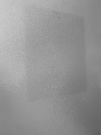 A black and white photo of a dark blue box and a grey-ish purple wall. The black and white makes it easier to see in a photograph the color difference.