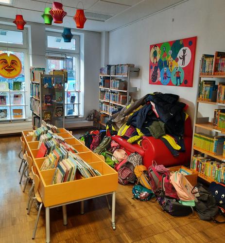 Foto vom Kinderbereich der Bücherei Kaiserswerth mit einem Haufen Kinderjacken auf dem Sofa.