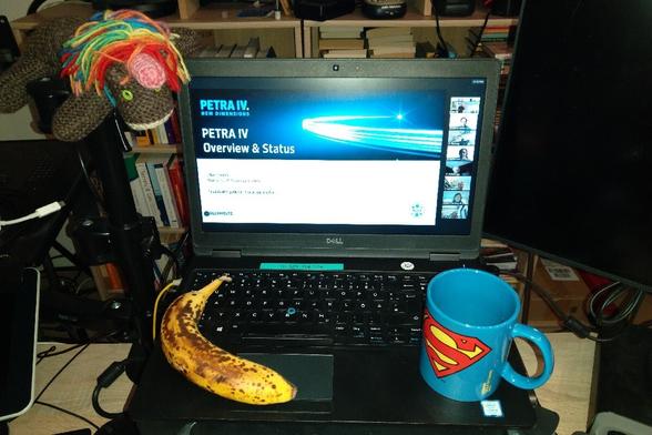 Foto: Laptop mit Präsentationstitel "Petra IV Overview & Status"; dazu Banane, Kaffee, gestricktes Einhorn.