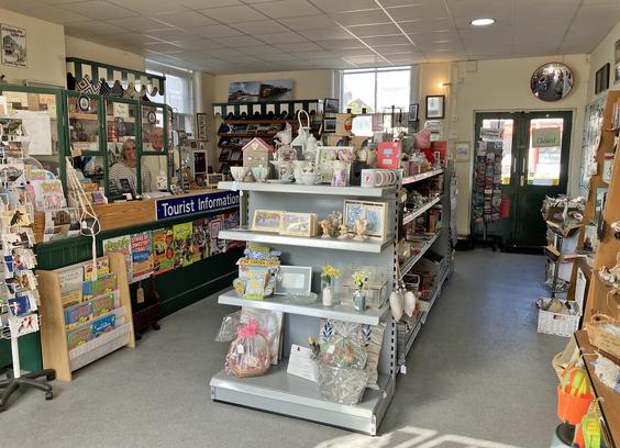 Photo of the inside of a shop offering gifts, souvenirs, books, coffee, and tourist information. Two staff are standing behind the counter.
