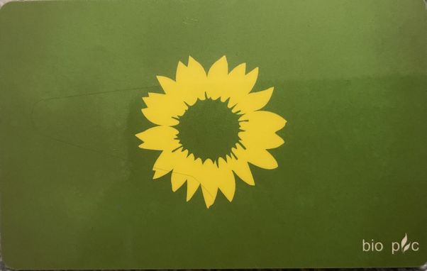 Mitgliedskarte Bündnis90/Die Grünen. Vor dem Grünen Hintergrund ist eine gelbe Sonnenblume mittig angebracht, deren Inneres ebenfalls grün ist.