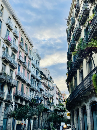Speckled morning skies above a rare wide street in El Born, Barcelona, with modernist buildings.