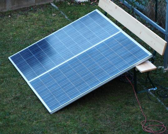 Zwei gebrauchte PV Module liegen provisorisch aufgeständert auf einer Bierbank.