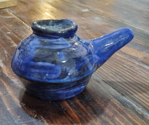 Small blue ceramic neti pot on a wooden tabletop