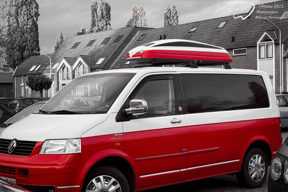 A rather modern Volkswagen van with a ski box on the roof both painted in red and white. The ski box looks like a high speed train.