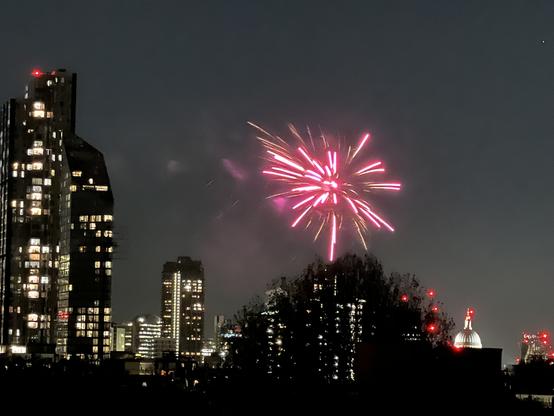 Red burst of fireworks above buildings, with skyscraper on left (City of London) and the dome of St Pauls on the right