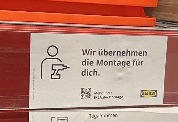 Schild an einem Regal im Ikea-Möbelhaus: „Wir übernehmen die Montage für dich.“