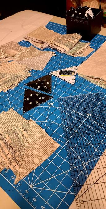 Triangle hackerboxes Tessellation PCBs, with LEDs, will go on a quilt backing, as a wall hanging. Pictured is the cutting table with the piecing laid out and three of the PCBs shown.
