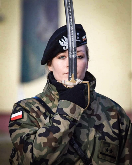 Oficerka Wojska Polskiego w czarnym berecie prezentuje szablę.