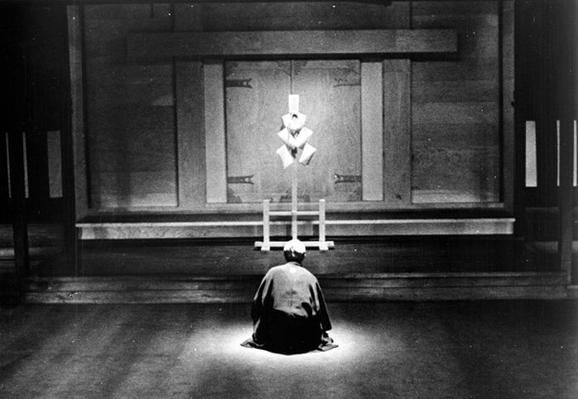 A man kneeled in front of a Shinto altar.