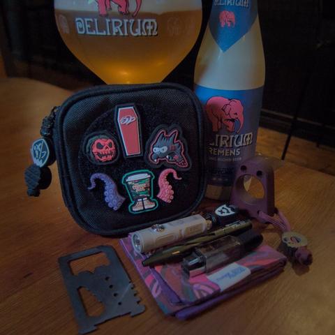 EDC loadout next to a bottle and glass of Delirium beer
