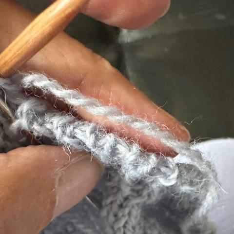 View of the knitting from top. The bound off stitches look like regular knit stitches which turn the edge.