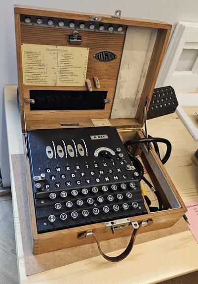 A mechanical cipher machine. It sits inside a wooden suitcase, looks like a typewriter with some code wheels on top.