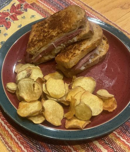 Reuben's sandwich and chips on a red plate.