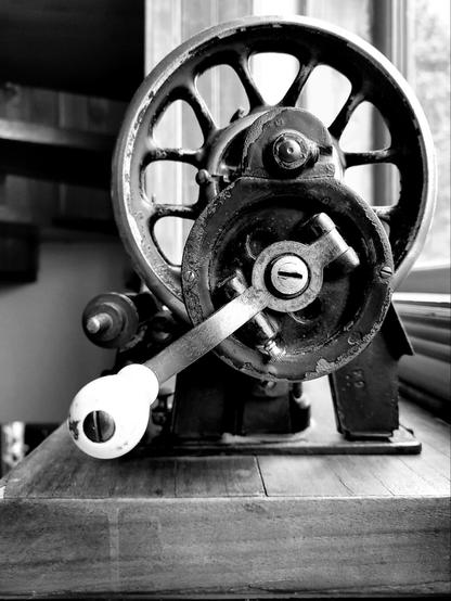 Black and white photo of old sewing machine in a window sill