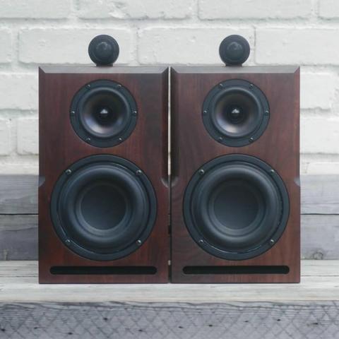 Two walnut bookshelf speaker sitting side by side. The grain across the face of each speaker is book matched.