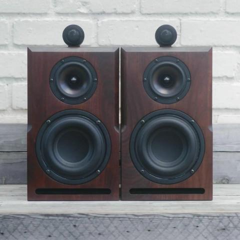 Two walnut bookshelf speaker sitting side by side. The grain across the face of each speaker is book matched.