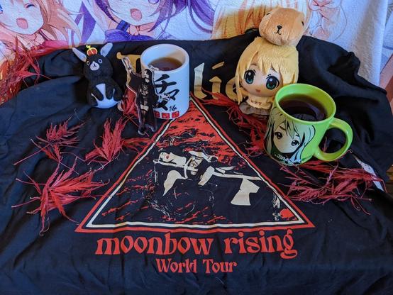 Mugi, Anko, and Hima have mugs of tea. Around them are red Japanese Ornamental Maple leaves. They are on a T-shirt saying moonbow rising world tour