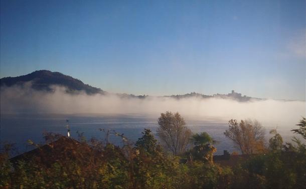Mount Saint Quirico and Castle of La Rocca, in Angera, province of Lombardy, in the morning mist. At the front, Lake Maggiore. 

Both made onboard of the Eurocity 32 train, from Milan to Geneve.