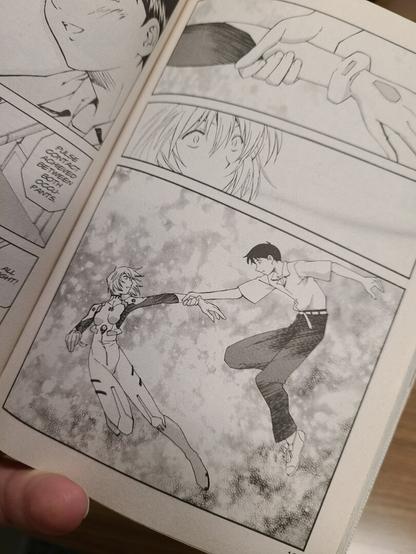 Photograph of a page from the first volume of Neon Genesis Evangelion: The Shinji Ikari Raising Project. It shows various black and white scenes, with a highlight on a scene where Shinji dressed in his school uniform is reaching down to Rei who is dressed in her lug suit reminiscent of Michelangelo's Sistine Chapel design of God reaching out to Adam