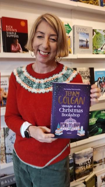AUthor Jenny Colgan, in Christmas jumper, with her new novel, Midnight at the Christmas Bookshop, in the Edinburgh Bookshop
