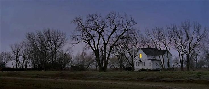 A view of a small white farmhouse in a rural area
