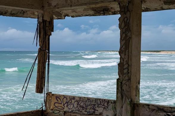 Crumbling, graffitied concrete and rebar frame the beautiful sea.