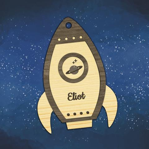 Décoration de Noël en bois découpé et gravé en forme de fusée avec vue sur une planète à travers son hublot et personnalisée avec le prénom de votre choix. A retrouver dans notre boutique en ligne : ernestine-etcie.fr