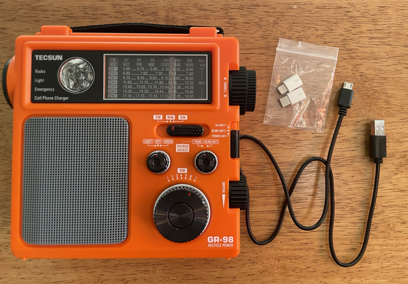 Front view of the Tecsun GR-98 showing the charging cable plugged in and the adaptor fittings that came with it.