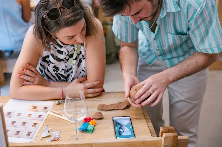 A photograph of someone sculpting clay under the guidance of an experienced tutor.