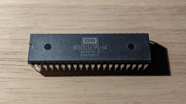 A 40 pins DIP package WDC 65c02 processor,  essentially a large black computer chip with some grey markings on top.