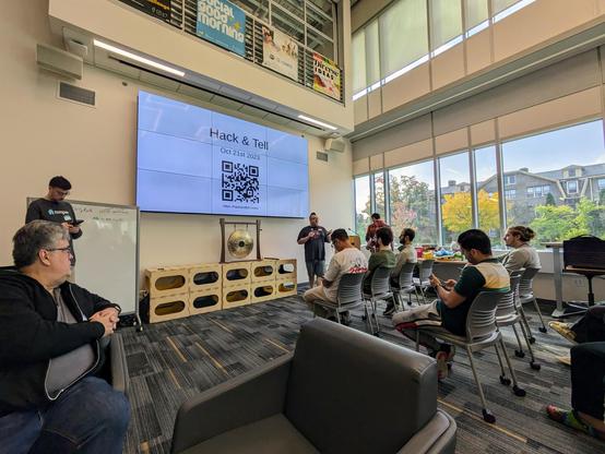 A group of people who are seated and watching a speaker at the front of a room
