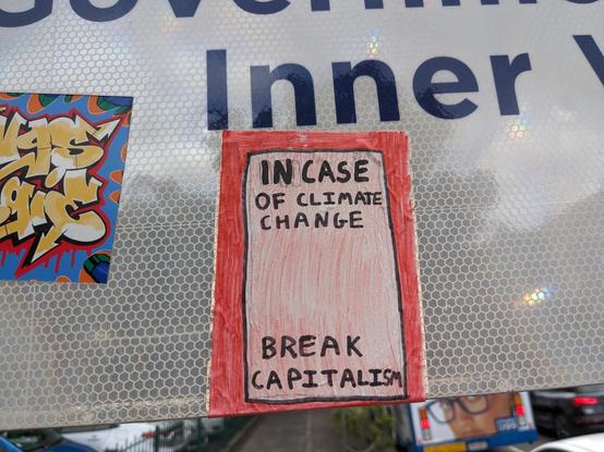 Sticker on a sign that says "In case of climate change, break capitalism"