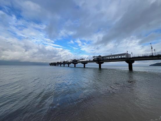 Eine Holzmole in das Meer hinaus mit kleinen Verkaufsständen.