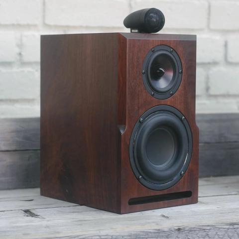 A solid walnut bookshelf speaker sits on a bench.
